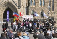 Na schodišti opatřeném vlajkami Filipín, Kanady a Izraele se chystají hudebníci na jakousi „globální modlitbu“.