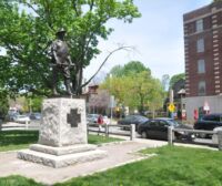 Socha maníka s puškou v ruce.